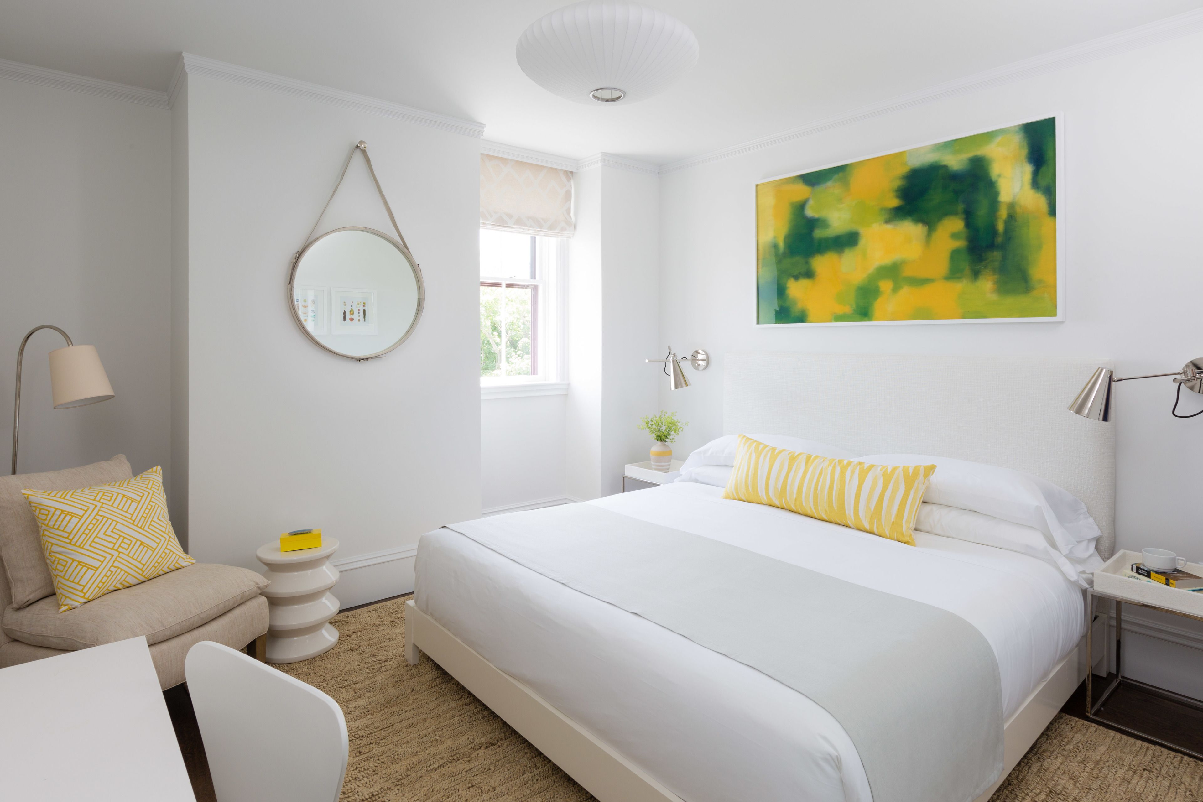 Quarto moderno com cama grande, mesas de cabeceira, um espelho redondo e janela com vista.