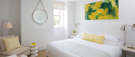 Quarto moderno com cama grande, mesas de cabeceira, um espelho redondo e janela com vista.