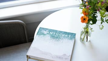 A book titled "NANTUCKET" on a white table with a vase of flowers.