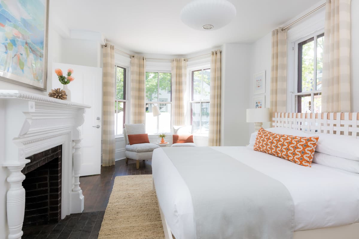 A bedroom with a large bed, a fireplace, and a view of the outdoors.