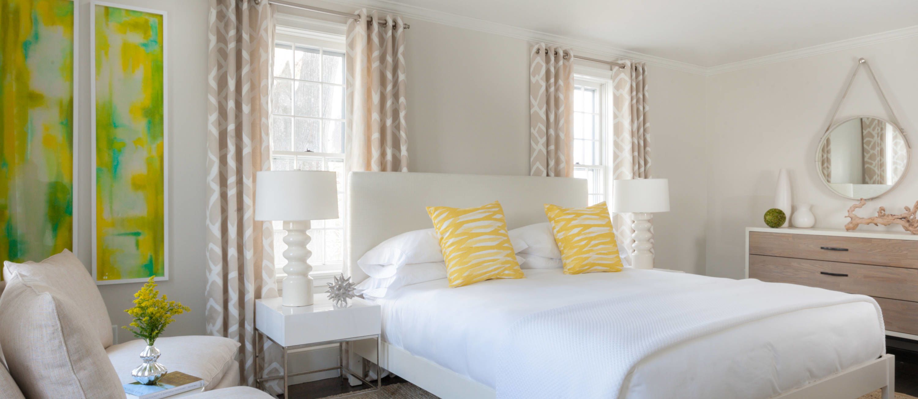 A bedroom with a large bed, two bedside tables, a nightstand, a dresser, and a mirror.