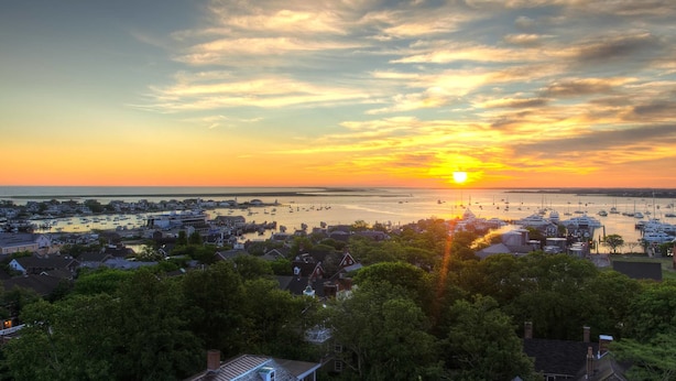 A coastal town at sunset with boats in the harbor and residential buildings in the foreground. - 21 Broad Hotel (Nantucket)