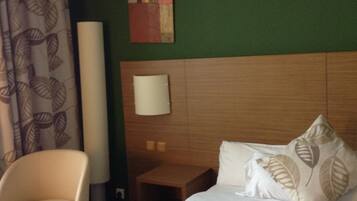 A hotel room with a bed, a chair, a nightstand, and a wall art piece.