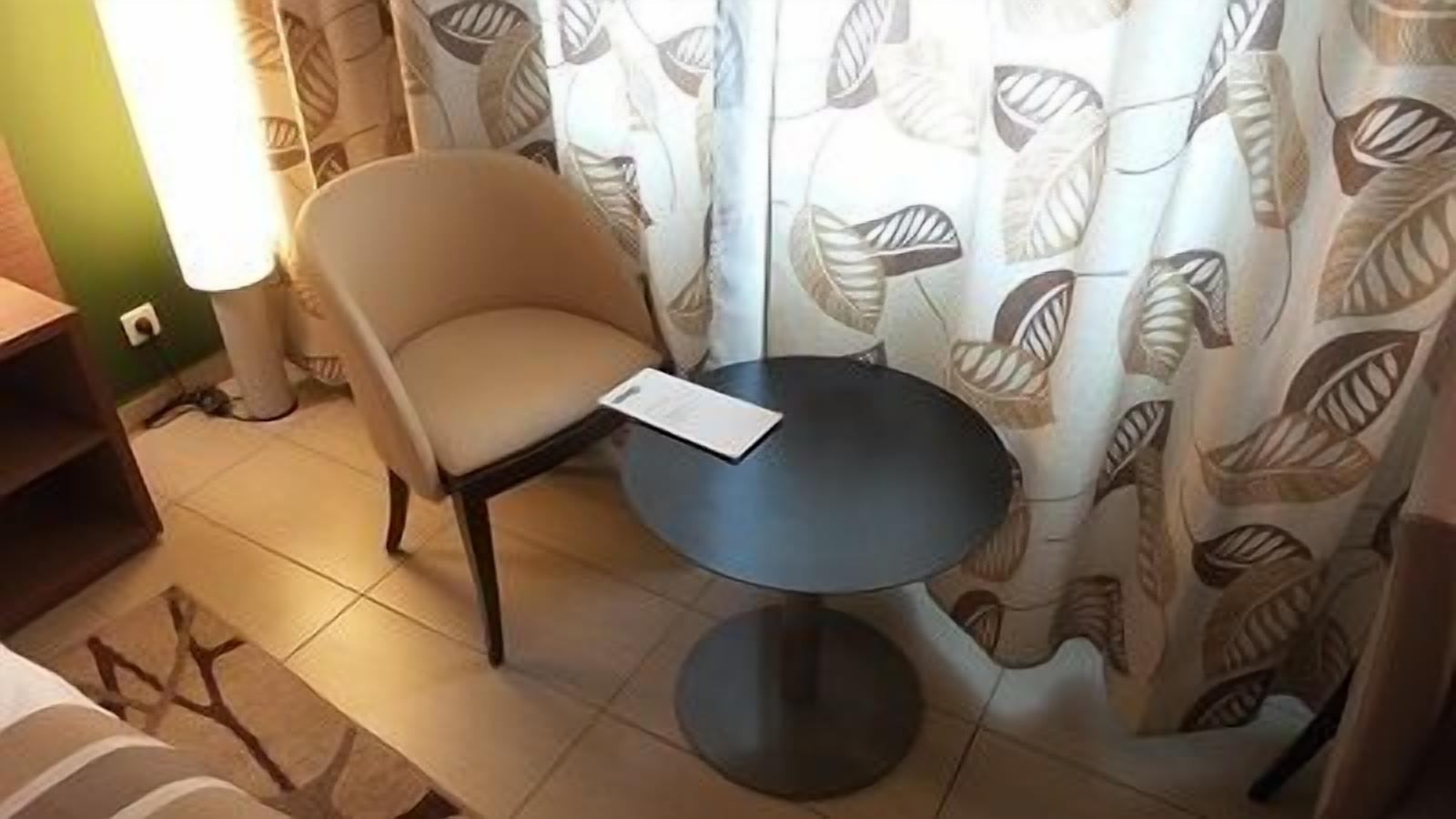 A small room with a round table, a chair, and a curtain with a leaf pattern.