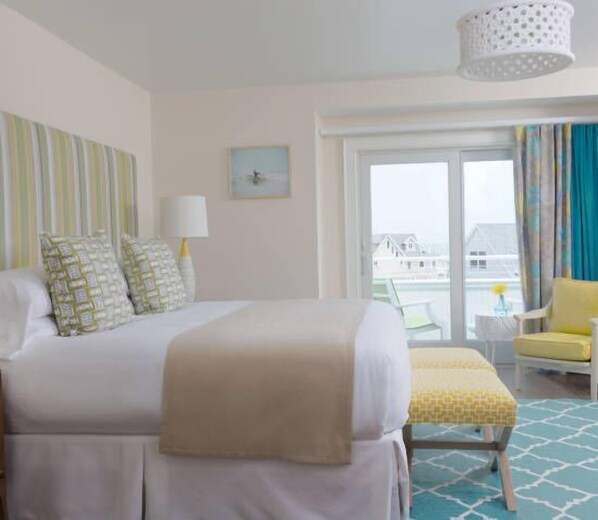 A hotel room with a large bed, a bedside table with a lamp, a chair, and a view of the outside.