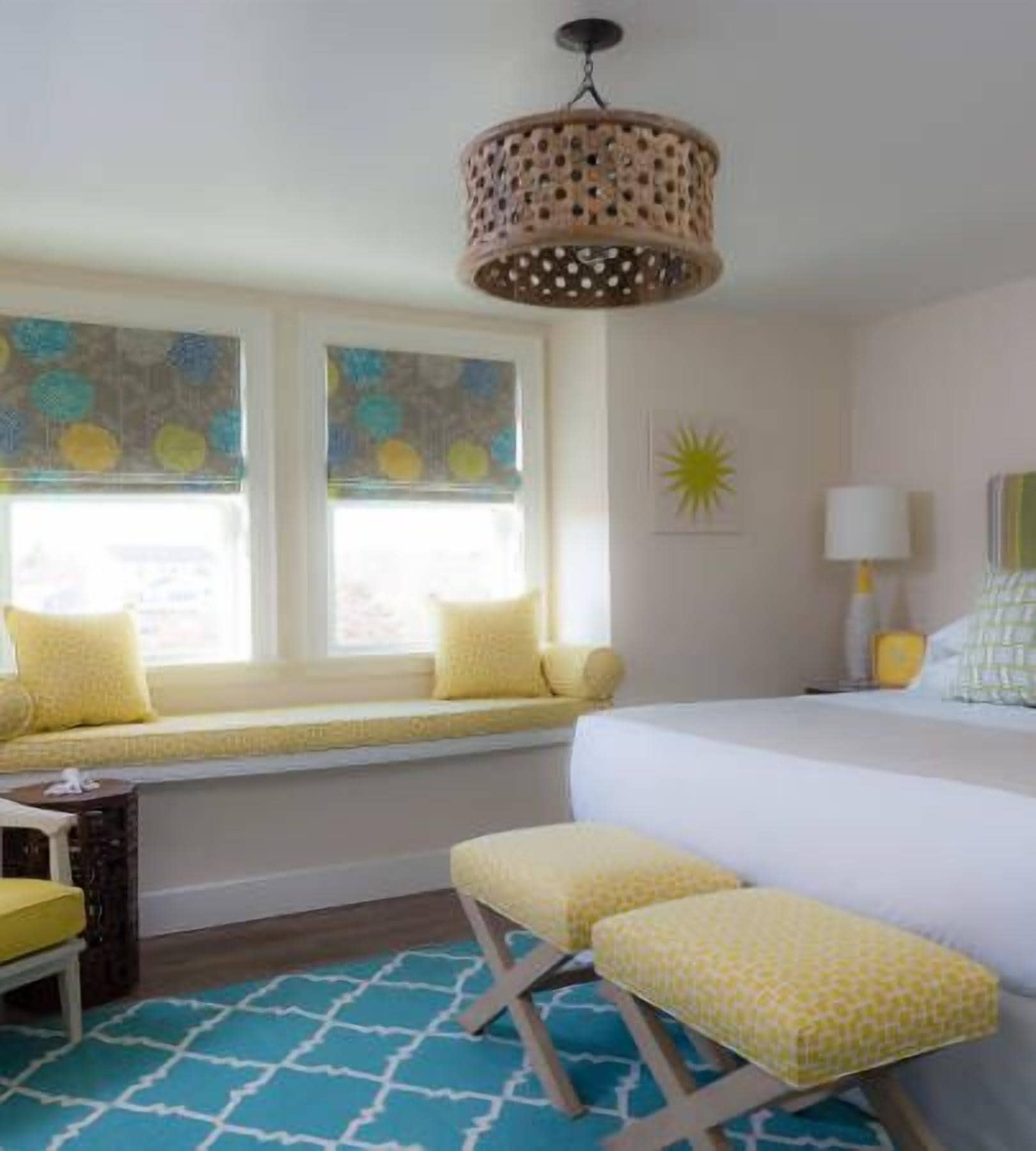 A bedroom with a bed, bench seating, a window seat, and a hanging light fixture.