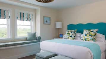 A bedroom with a large bed, a window with a view, a bedside table, and a lamp.