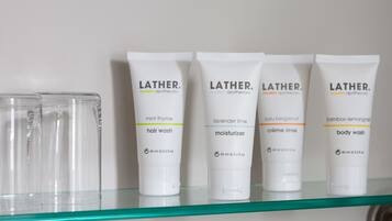 A shelf with five Lather modern apothecary products: hair wash, moisturizer, creme rinse, and body wash.