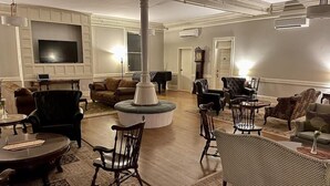 A spacious living room with a large TV, multiple seating options including a sofa and chairs, a fireplace, and a decorative pillar. - Brandon Inn (Brandon)