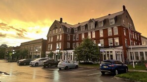 A multi-story building with a brick facade, large windows, and a parking lot with several cars. - Brandon Inn (Brandon)