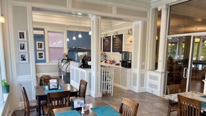 A restaurant with wooden tables and chairs, a kitchen area, and framed pictures on the walls. - Brandon Inn (Brandon)