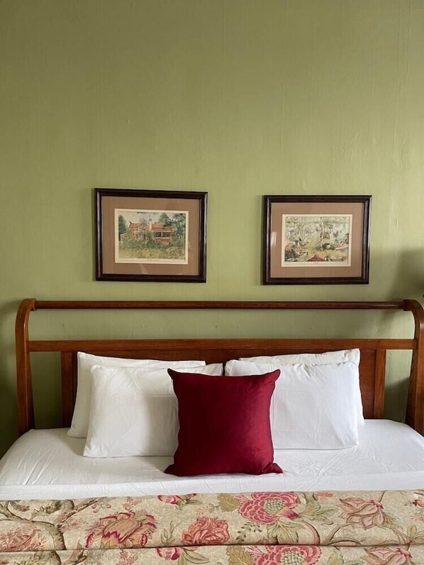 A bed with white and red pillows, a wooden headboard, and two framed pictures on the wall. - Brandon Inn (Brandon)