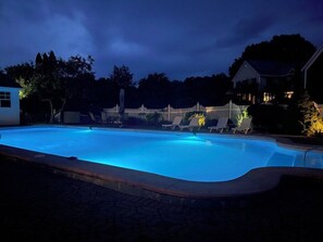 Una piscina con muelle de madera y sillas de descanso.