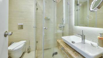 A modern bathroom with a glass-enclosed shower, a white toilet, and a marble countertop with a sink.