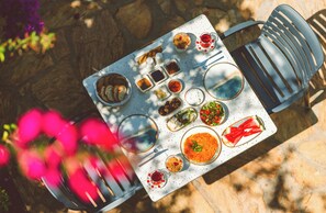 Una mesa dispuesta con diversos platos, salsas y una copa de vino tinto, sugiriendo un montaje para una comida al aire libre.