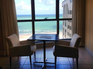 A room with a view of the ocean through large windows, two chairs, and a small table. - Eninova Flat Executive (Recife)