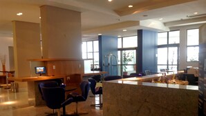 A lobby with a reception desk, seating area, and large windows. - Eninova Flat Executive (Recife)