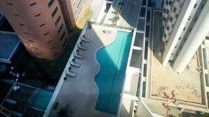 An aerial view of a modern building with a swimming pool, multiple balconies, and a parking area. - Eninova Flat Executive (Recife)