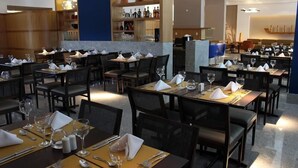 A restaurant with multiple tables set for dining, each with a white napkin, silverware, and wine glasses. - Eninova Flat Executive (Recife)