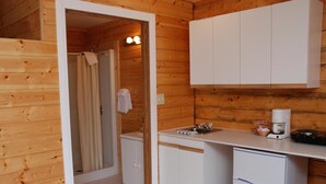 A compact kitchen with white cabinets, a coffee maker, and a sink. - Triple J Hotel & Cabins (Dawson City)