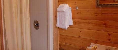 Un baño con paneles de madera, ducha, lavamanos y espejo.