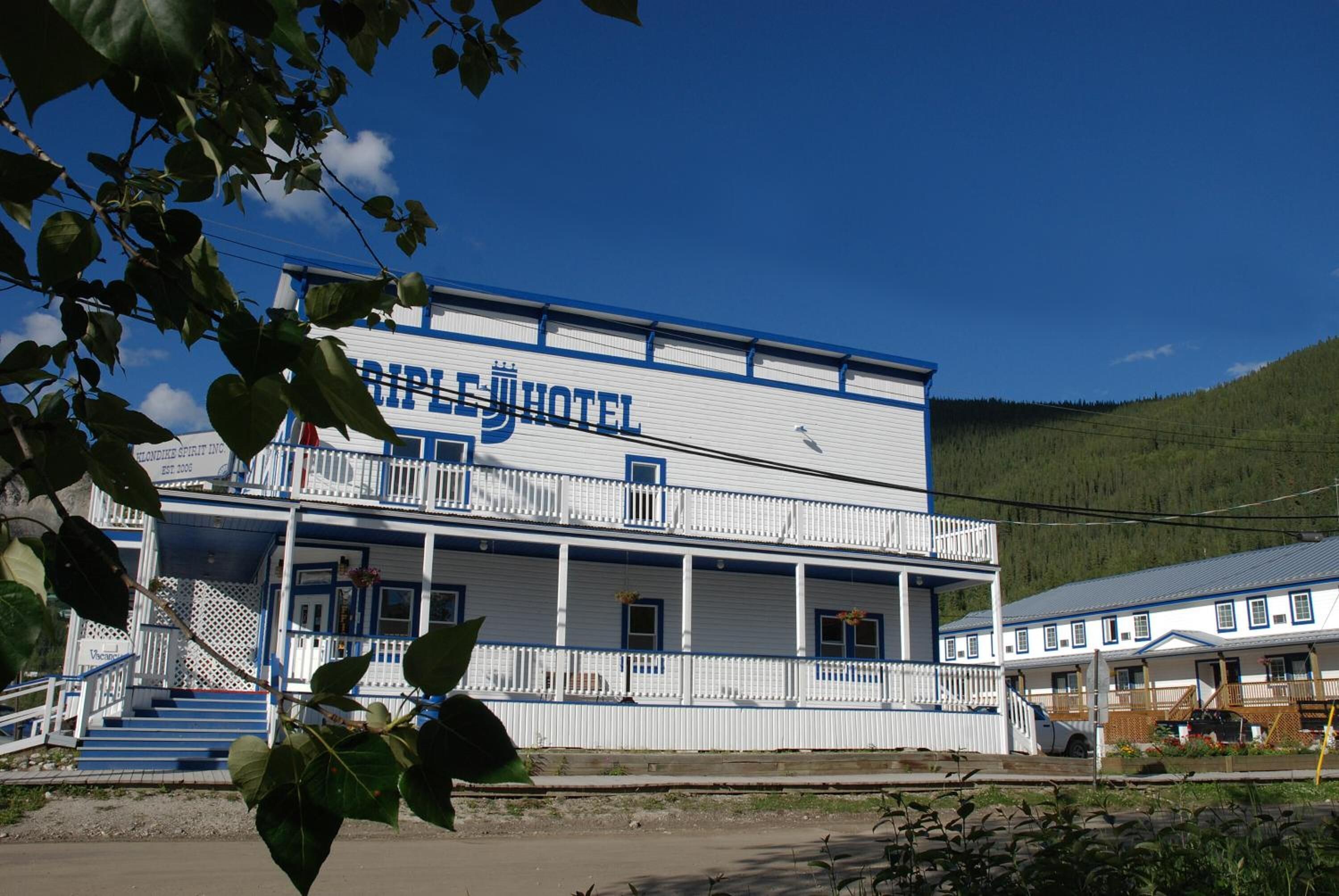 A two-story building with a balcony and a sign reading "TRIPLE J HOTEL".
