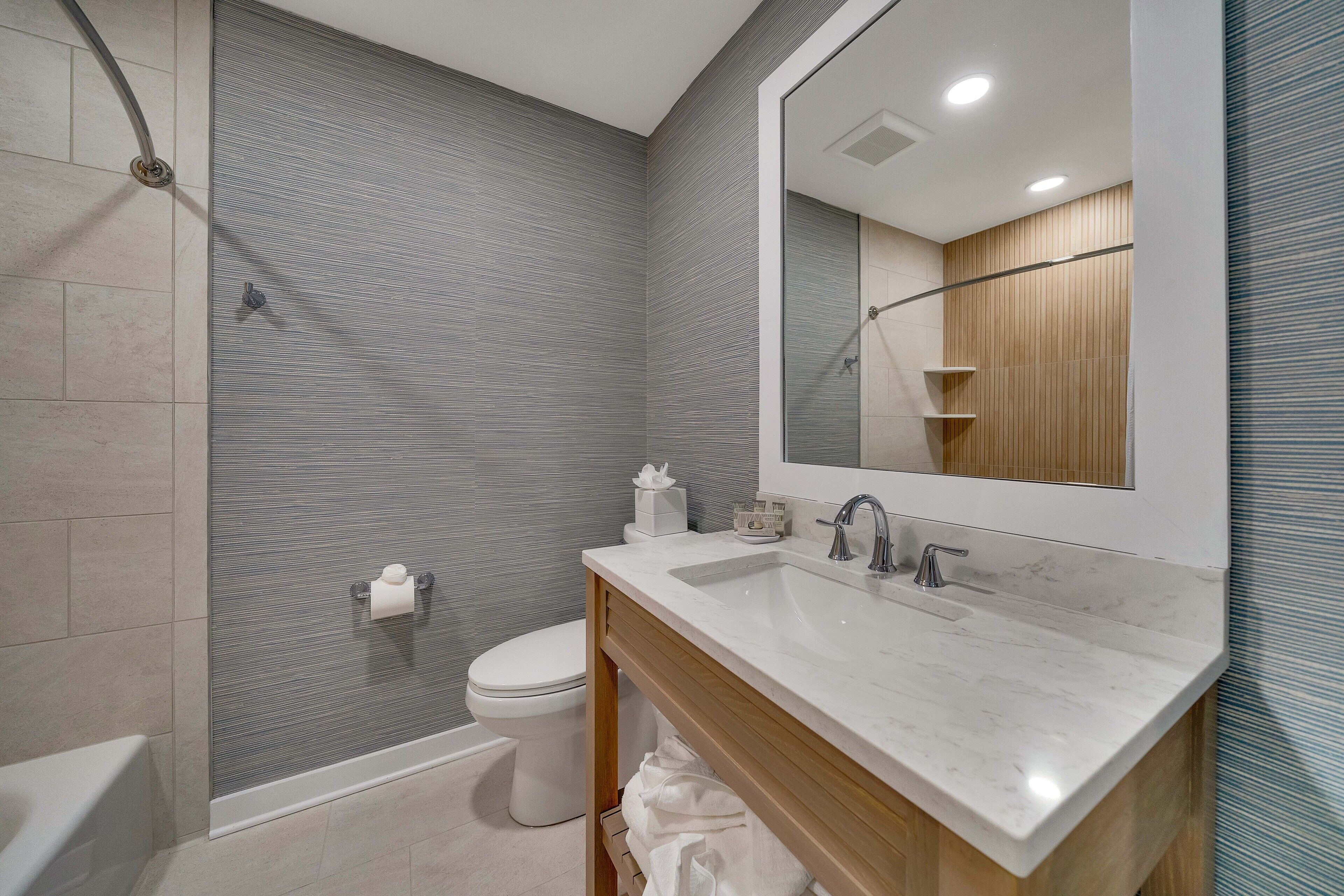A modern bathroom with a shower, toilet, and sink.