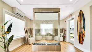 A modern interior with a glass partition, a potted plant, a wooden structure, and a surfboard on the wall.