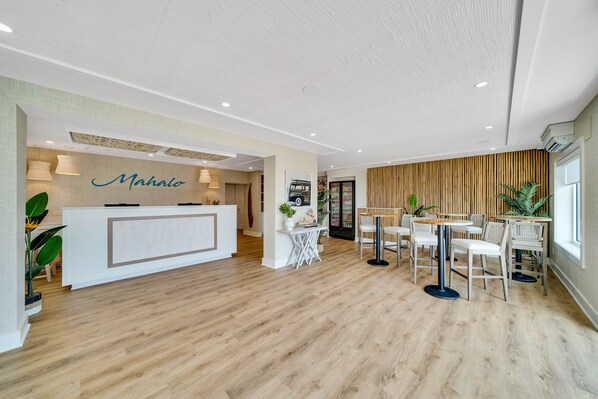 A modern hotel lobby with a reception desk, seating area, and a wooden wall. - Mahalo Cape May (Cape May)