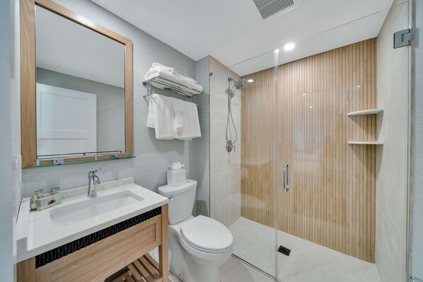 A modern bathroom with a glass-enclosed shower, a white sink, and a toilet.