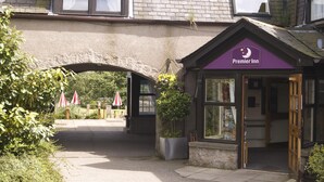 L'ingresso di un hotel Premier Inn con un arco in pietra, un tendone viola e una pianta in vaso.