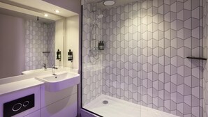 Un bagno moderno con doccia, due lavandini e un ampio specchio.