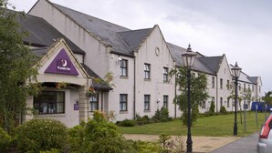 Un hotel con un evidente cartello 'Premier Inn', un prato curato e uno stile architettonico classico.