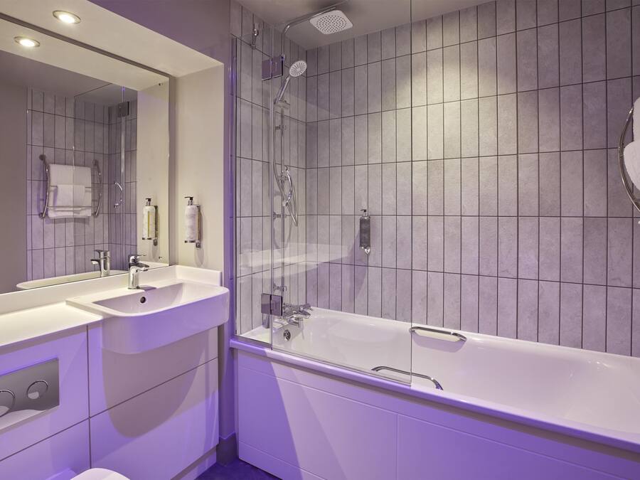 Un baño moderno con bañera, dos lavamanos, ducha y un espejo grande.