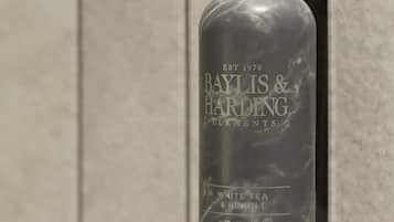 Una botella de Baylis & Harding Elements con dosificador bomba, colocada sobre un muro de azulejos.
