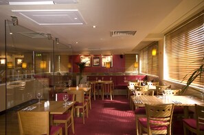 A restaurant with wooden tables and chairs, red carpet flooring, and large windows with blinds. - Premier Inn Aberdeen City Centre (Aberdeen)