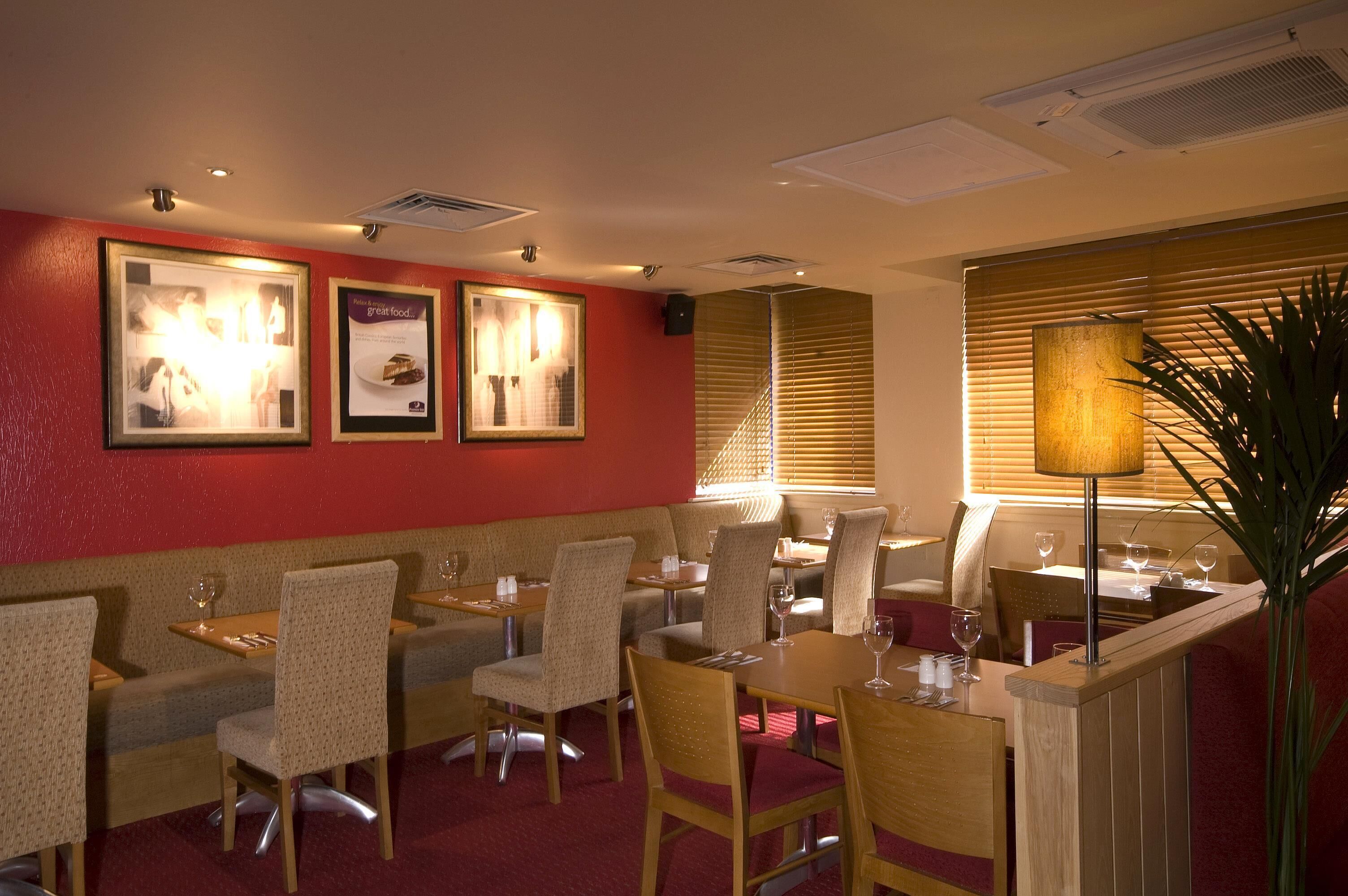 Un restaurant avec des banquettes et des tables, des tableaux encadrés aux murs et une plante dans un coin.