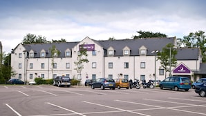 Een hotel met meerdere parkeerplaatsen, een plat dak en een bord waarop staat dat het een Premier Inn is.