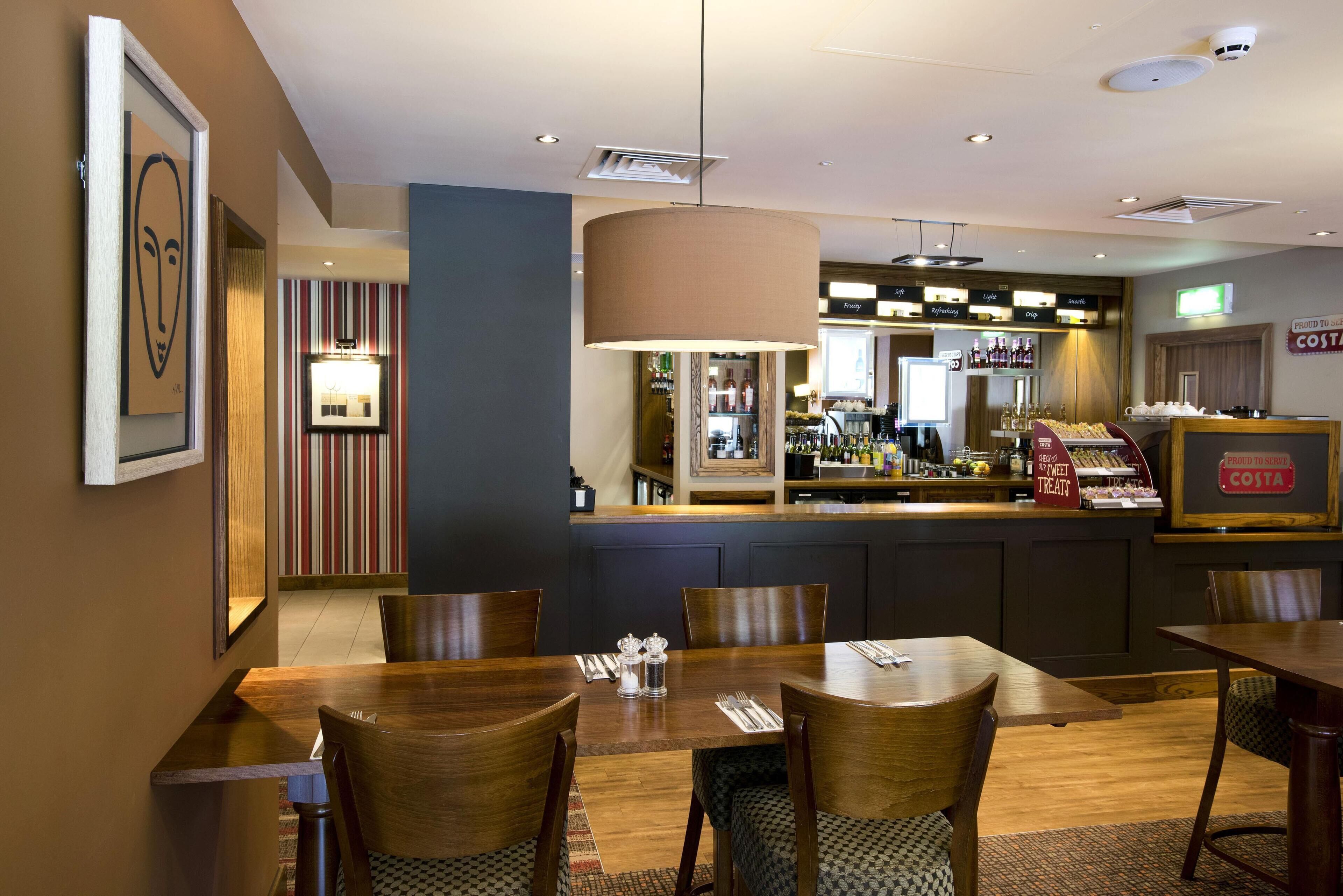 A restaurant with a bar area, wooden tables, and chairs.