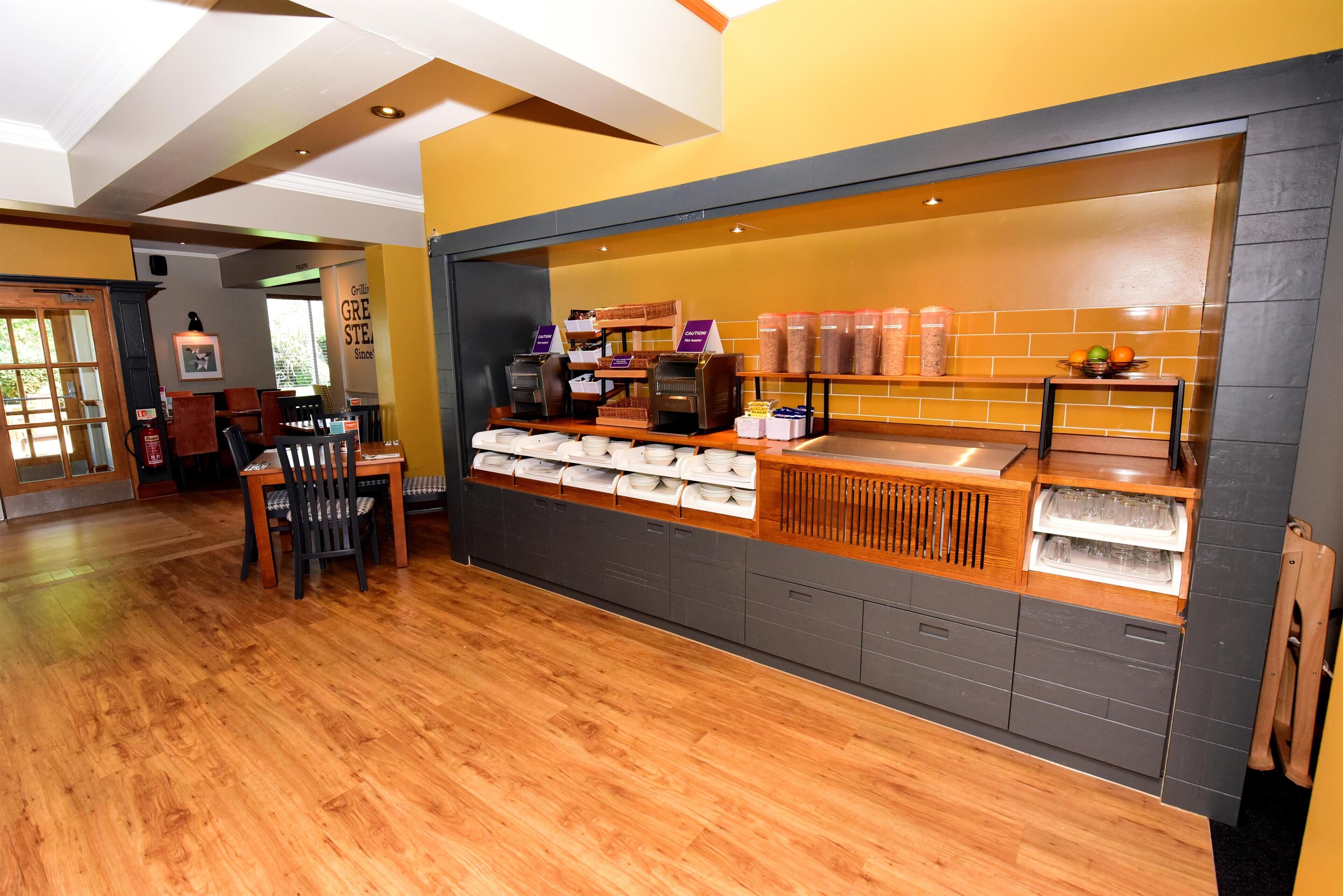 A café with a wooden counter, seating area, and a tiled backsplash.