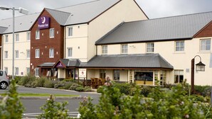 Un hotel con un evidente cartello Premier Inn, un ristorante chiamato 'The Harbour' e un'area di parcheggio con un'auto.