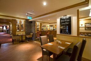 A restaurant with wooden tables and chairs, a bar area, and a chalkboard menu. - Premier Inn Lisburn (Lisburn)