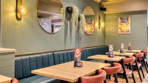 A restaurant interior with booths, tables, and wall-mounted mirrors. - Premier Inn Birmingham City - Aston (Birmingham)