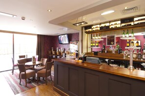 A bar area with a counter, seating, and a television screen. - Premier Inn Stratford-Upon-Avon Waterways (Stratford-upon-Avon)