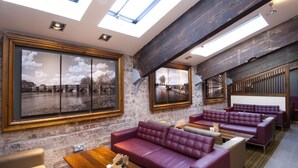 Un intérieur moderne avec un mur en briques, de grandes fenêtres et un coin salon doté de canapés en cuir.