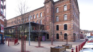 Un bâtiment historique en briques, doté d’une entrée en verre et portant l’inscription « Premier Inn », ainsi qu’une structure moderne en verre attenante.