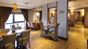 Un'area ristorazione in un hotel con un tavolo di legno, sedie e un lampadario.