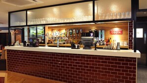 A bar area with a counter, a cash register, and a variety of bottles and glasses.