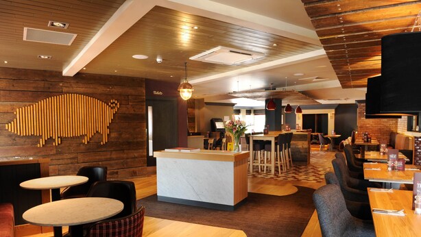 A restaurant with a wooden interior, a reception desk, and multiple seating areas.