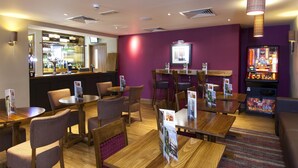 A restaurant with wooden tables and chairs, a bar area, and a jukebox. - Premier Inn Shrewsbury Town Centre (Shrewsbury)